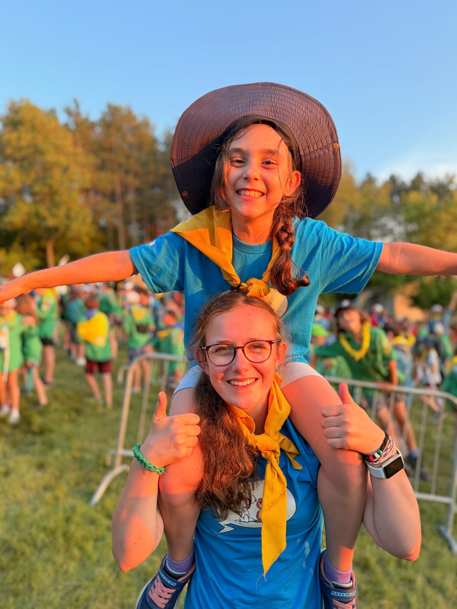 Une animatrice porte une jeune castor sur ses épaules lors d’un rassemblement ; toutes les deux sourient.